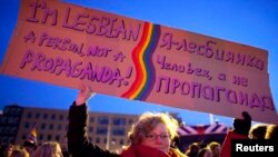 A woman holds up a banner during a demonstration by the gay community during a visit from Russian President Vladimir Putin to the Netherlands, in Amsterdam.