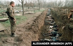 Солдат російської армії оглядає на кладовищі у столиці Чеченської Республіки тіла чеченських мирних жителів, убитих під час зимових боїв і ексгумованих для ідентифікації. Грозний, 31 березня 1995 року