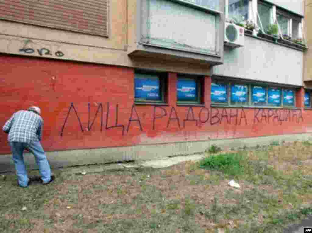 Мужчина закрашивает надпись "Улица Радована Караджича" в Белграде, 24 июля 2008