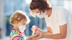 Majka čisti djetetu ruke sredstvom za dezinfekciju