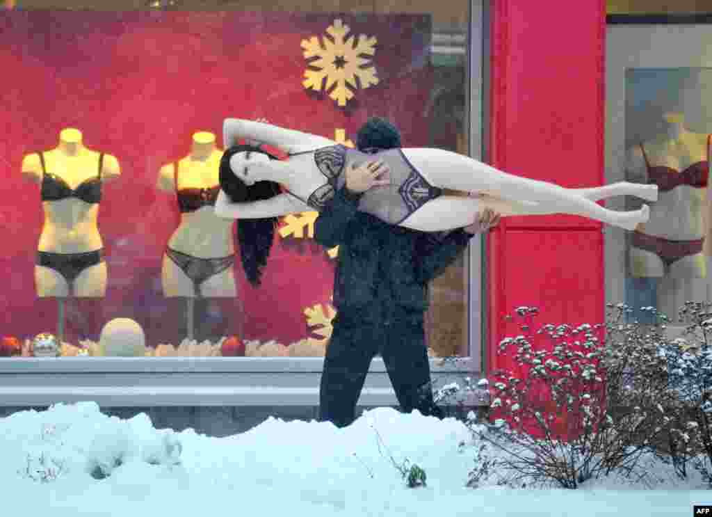 A man carries a mannequin down a snowy street in the Belarusian capital, Minsk. (AFP/Viktor Drachev)