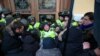 Міхеїл Саакашвілі (праворуч) спостерігає, як мітингувальники, яких він закликав йти до Жовтневого палацу, під час штурму будівлі виривають бійця Нацгвардії зі строю перед центральним входом до палацу. Київ, 17 грудня 2017 року 