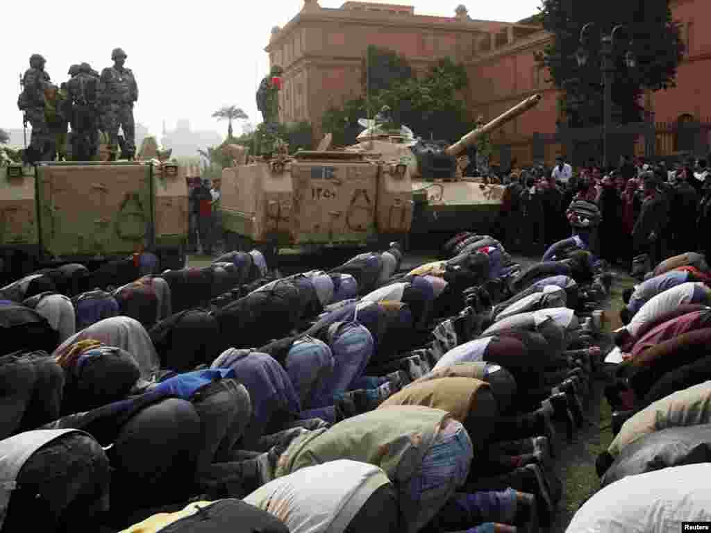 Protesters pray next to military personnel standing atop their vehicles in Cairo on January 29.