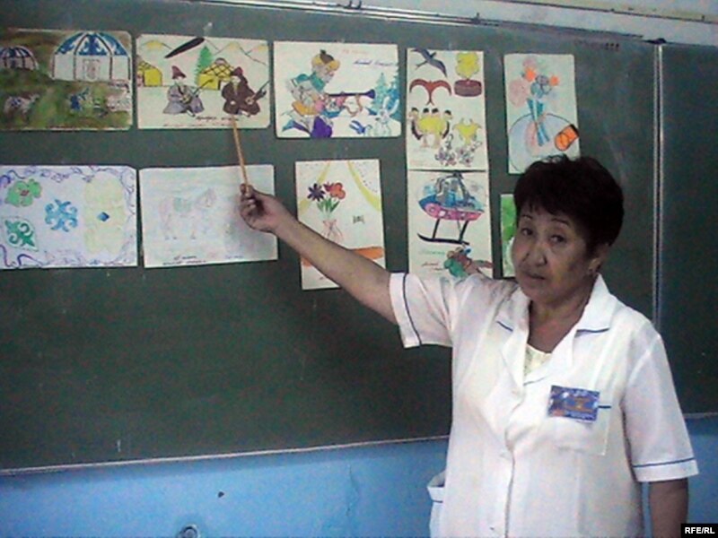 Преподаватель Зоя Ерманова показывает на детские рисунки Максата Айтбаева. Аул имени Нокина, 10 августа 2009 года.