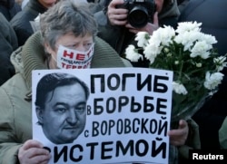 Женщина держит плакат с портретом Сергея Магнитского во время митинга в центре Москвы 15 декабря 2012 года