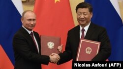 Russian President Vladimir Putin (left) and Chinese President Xi Jinping shake hands during a signing ceremony inside the Great Hall of the People in Beijing on June 8.