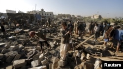 People gather at the site of an air strike in a residential area near Sanaa airport on March 26.