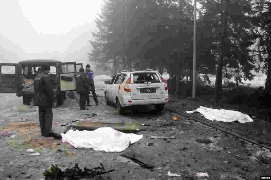 Men look at the covered bodies of victims at a site hit by shelling in Donetsk.