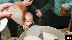 A boy stands among a line of people queuing for food at a charity distribution for poor people in Moscow.