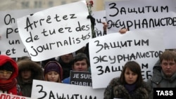 People hold placards as they pay tribute to the 12 people killed by two gunmen at the French weekly newspaper Charlie Hebdo's editorial office, outside French Embassy in Moscow on January 9.