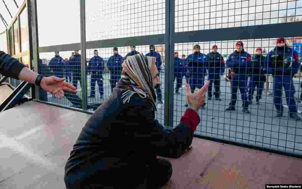 Muškarac pokazuje na mađarsku policiju s druge strane žičane ograde, koju je ta zemlja postavila 2015. godine kako bi sprečila ulazak migranata i izbeglica u zemlju