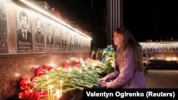 Жінка молиться біля стелі пам’яті загиблих пожежників-ліквідаторів аварії на ЧАЕС. Славутич Чернігівської області. 26 квітня 2019 року