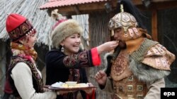 FILE: A woman (L) dressed in national costume offers traditional local dishes during Norouz celebrations in Bishkek.