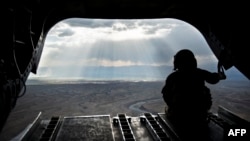 Американский солдат смотрит на горы афганской провинции Логар из вертолета "Чинук". Май 2014 года.