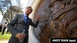 British sculptor Paul Day stands alongside his memorial honoring those who served in the Afghan and Iraq wars outside the Ministry of Defense in London in March 2017. 