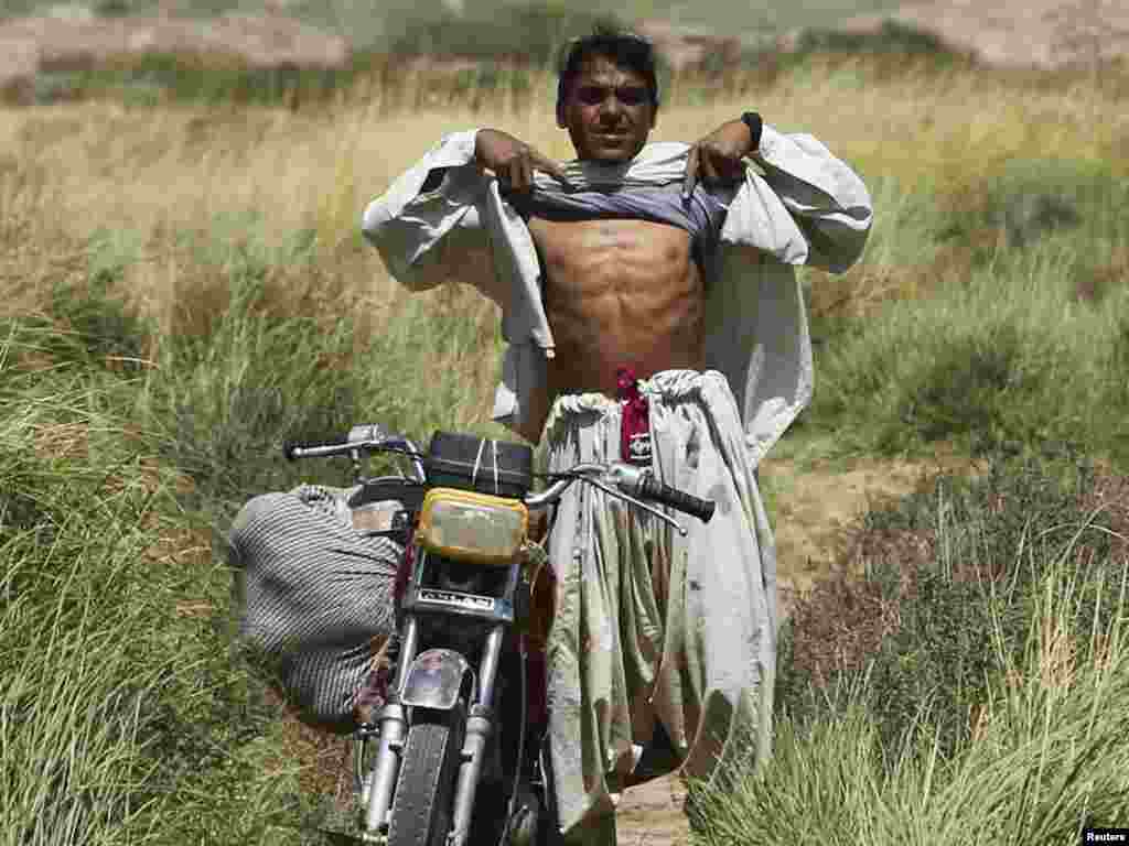 An Afghan villager raises his shirt to show that he is not wearing a suicide bomb vest to U.S. Marines from the 1st Light Armored Reconnaisance Battalion patrolling an area in Taghaz village in Helmand Province on September 9. Photo by Erik de Castro for Reuters