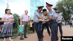 Law enforcement officers detain a man during an opposition protest in Almaty.