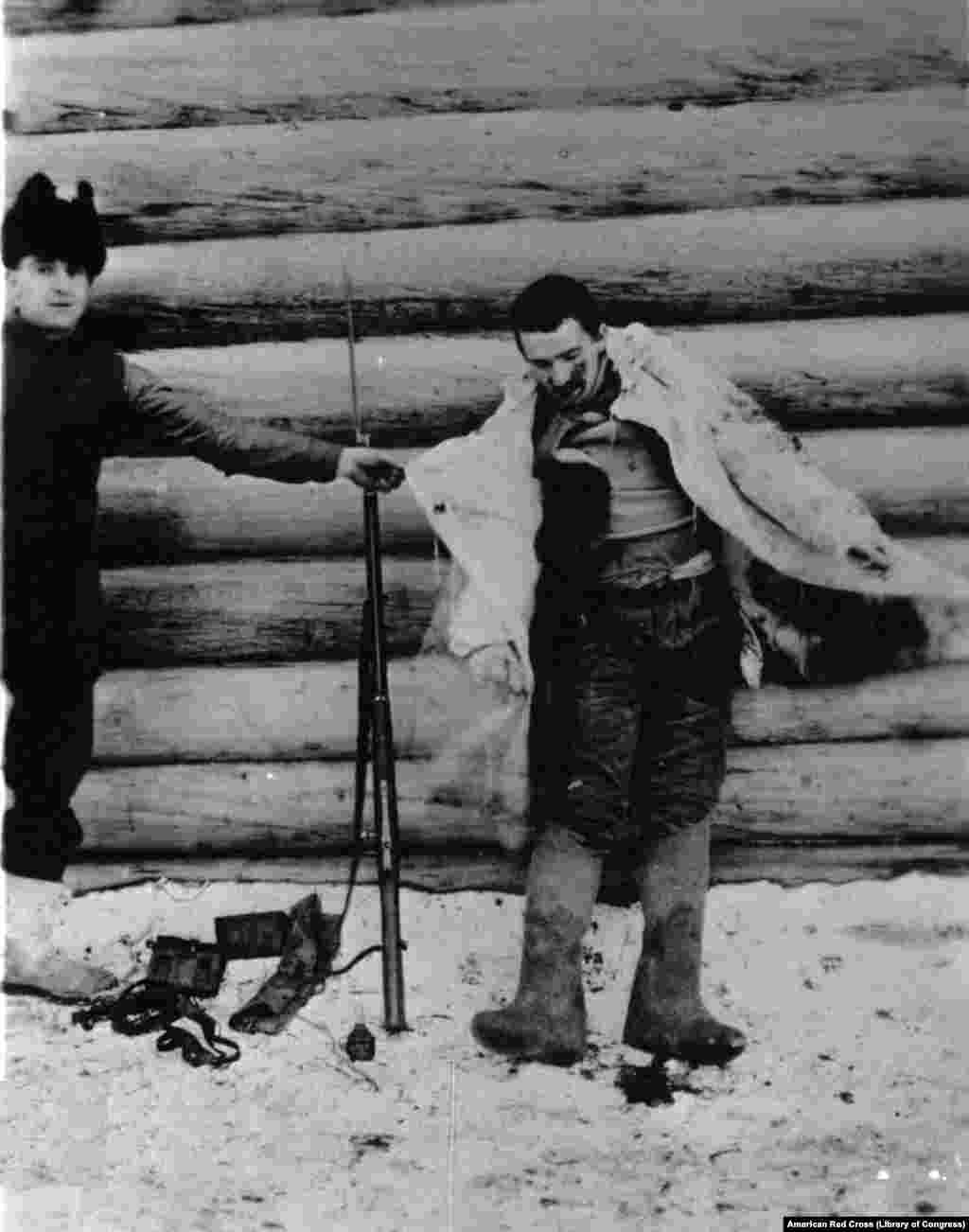 Американский военнослужащий показывает камуфляжную накидку на раненом большевистском солдате, который пытался пробраться к американскому гарнизону в Архангельске (фотография из архивов армии США)