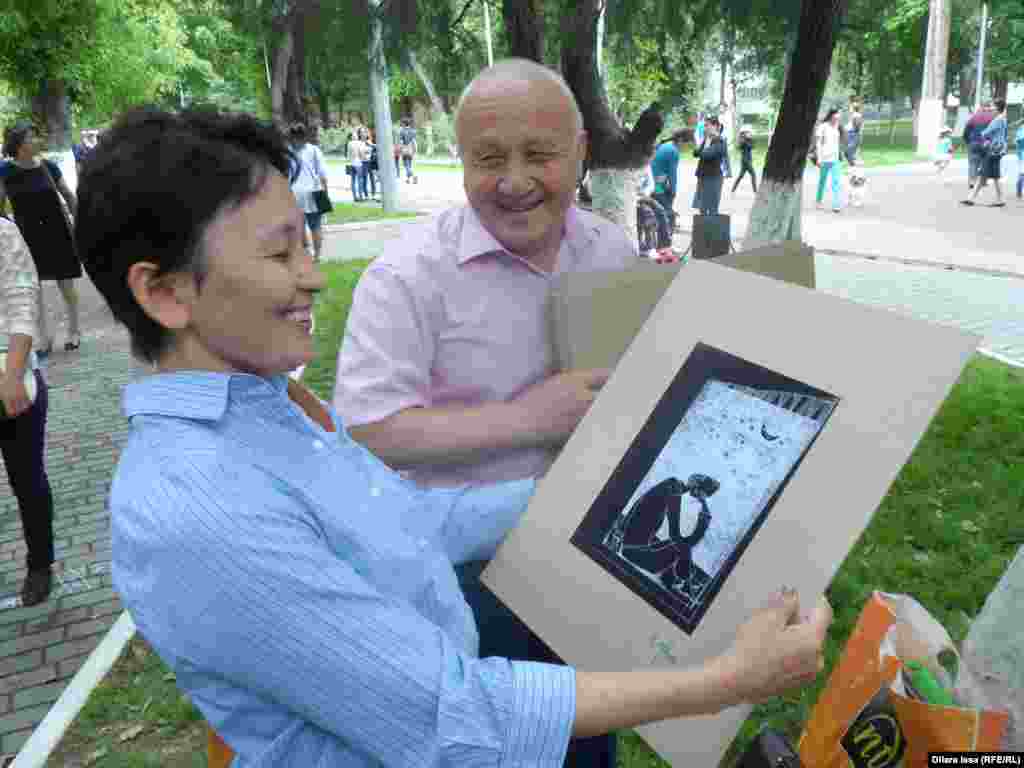 Художник Расул Естемесов дарит один из своих рисунков участнику фестиваля. 