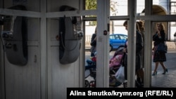 Севастопольцы проходят мимо старых телефонных автоматов на площади Лазарева, архивное фото