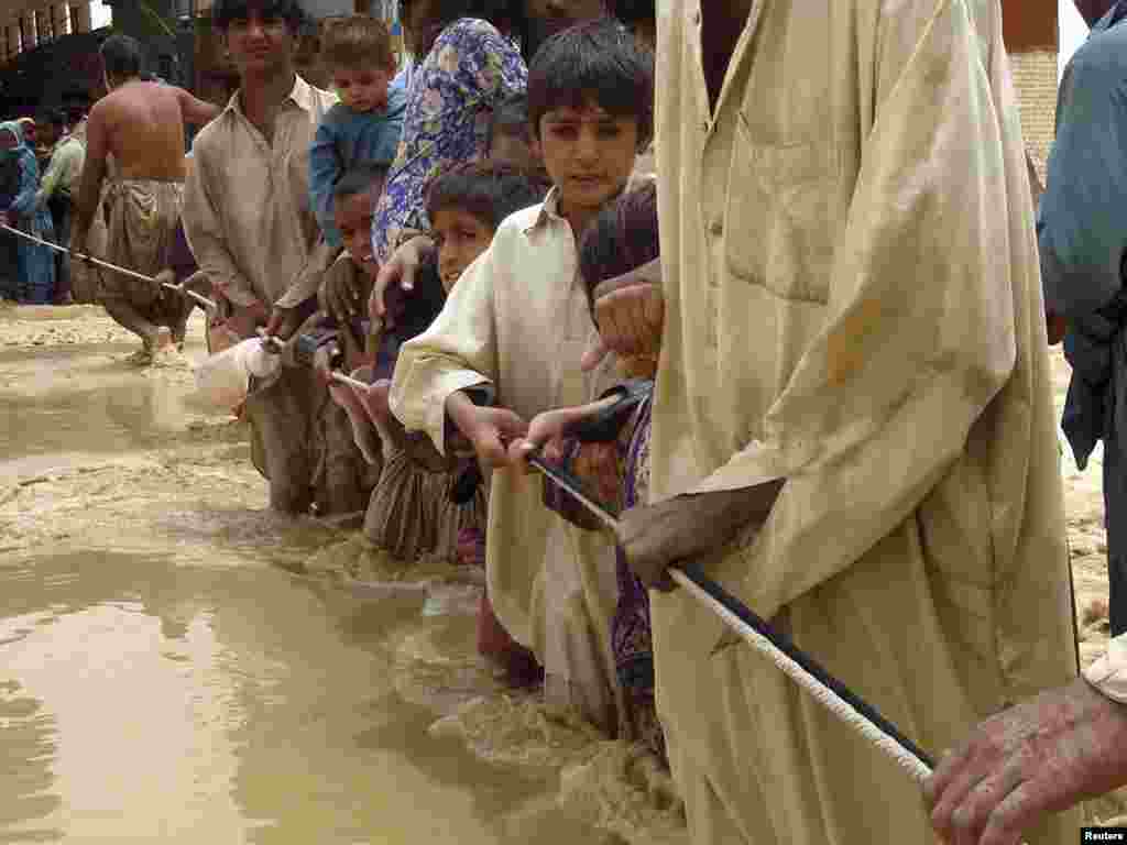 Residents cling to a rope as they walk through flood waters while evacuating the area after heavy rain in Pakistan's Baluchistan Province. Fifty people were killed when torrential rains unleashed flash floods in different parts of eastern Baluchistan. Photo by Reuters
