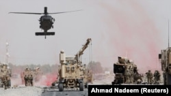 U.S. troops assess the damage to an armored vehicle belonging to the NATO-led military coalition after a suicide attack in Kandahar Province on August 2.