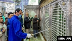 A man disinfects the Shrine of Masoumeh against coronavirus in the city of Qom, February 25, 2020