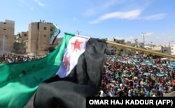 Syrian protesters wave their national flag as they demonstrate against the regime and its ally Russia in the rebel-held city of Idlib on September 7.