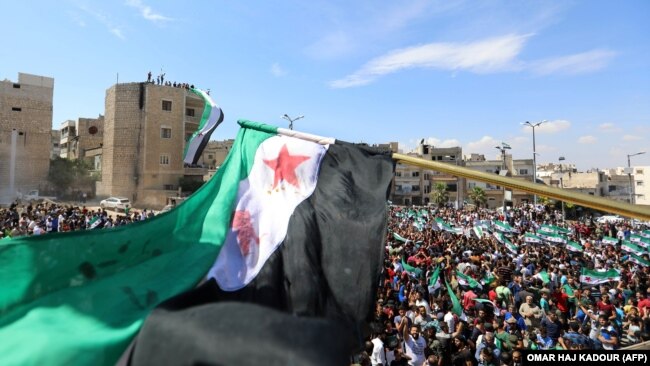 SYRIA - Syrian protesters wave their national flag as they demonstrate against the regime and its ally Russia, in the rebel-held city of Idlib on September 7, 2018