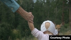 Мужчина держит за руку ребенка на ранчо для приемных детей в штате Монтана. 2011 год. Иллюстративное фото.