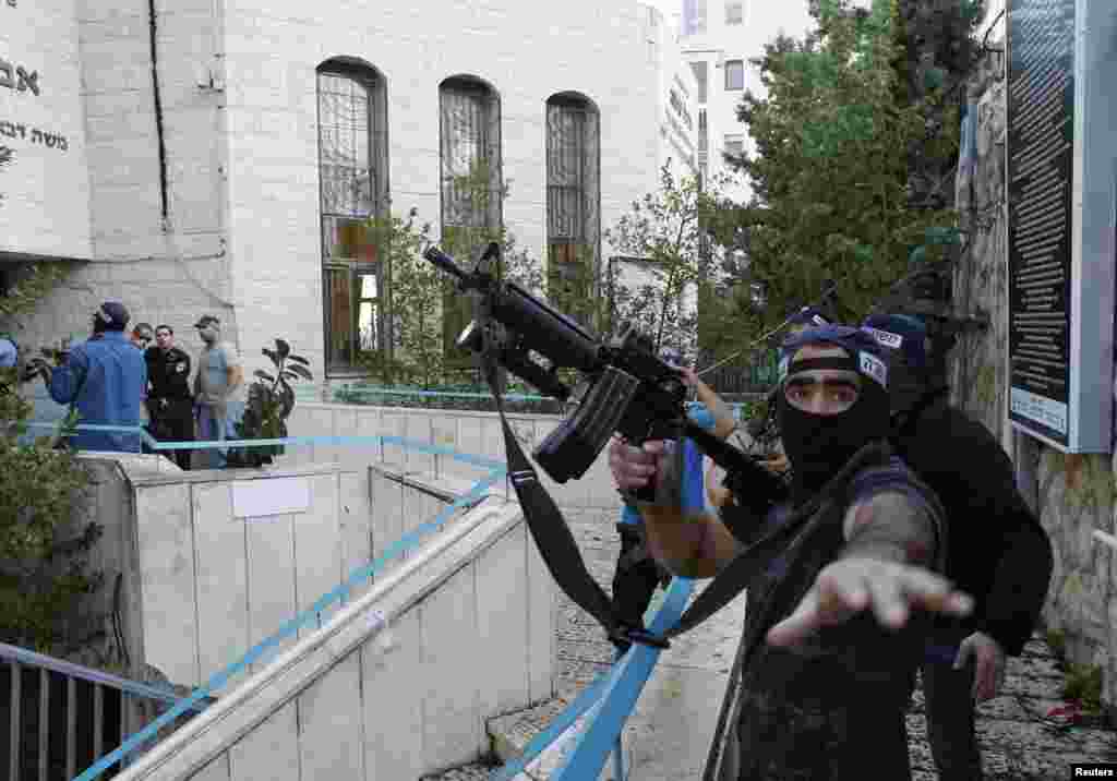 An Israeli police officer gestures as he holds a weapon near the scene of an attack at a Jerusalem synagogue. Two suspected Palestinian men armed with axes and knives killed four people before being shot dead by police, the deadliest such attack in the city in years. (Reuters/Ronen Zvulun)