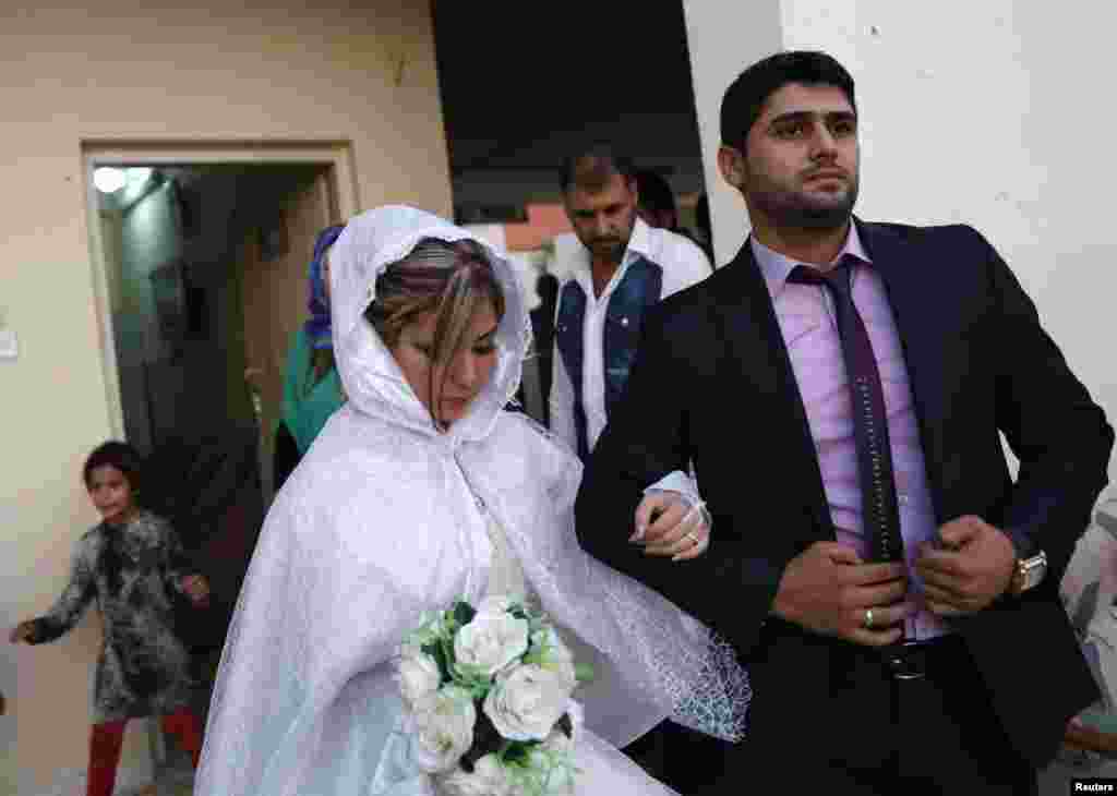Displaced Iraqi Shi&#39;ite Muslim Muhammad Harith Youssif, 25, walks with his 20-year-old bride, Reem Ahmed, a Sunni Muslim who fled violence in Mosul, during their wedding at a school in Baghdad. (Reuters/Thaier Al-Sudani)