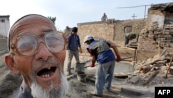 An ethnic Uzbek smiles as members of his family reconstruct their destroyed house in the village of Shark outside Osh, in October, 2010.