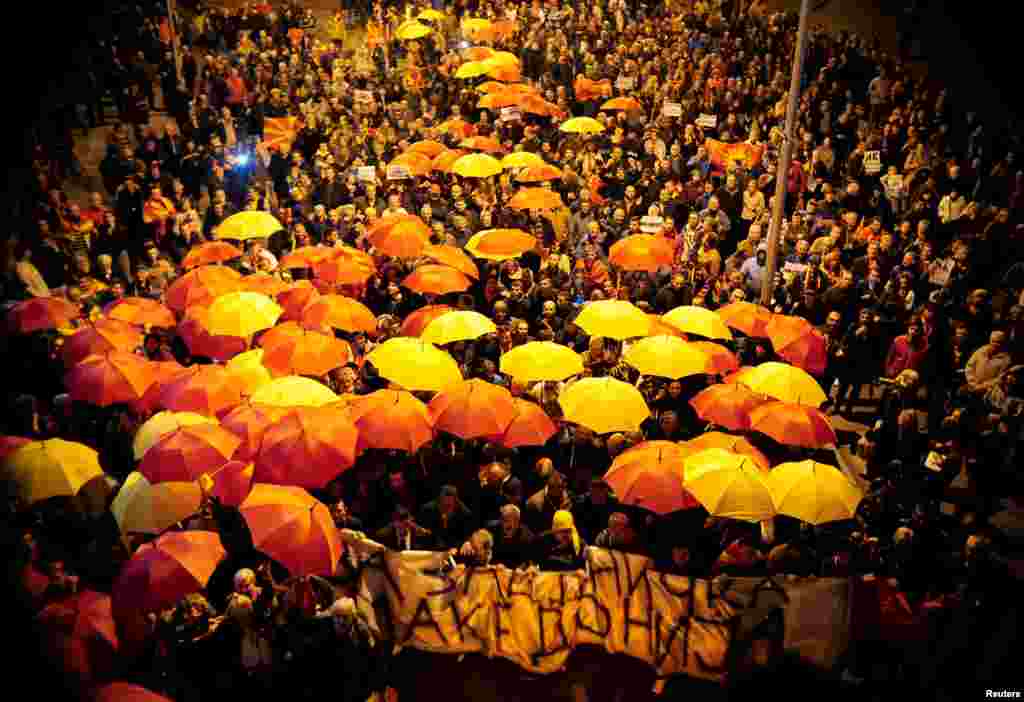 Protesters shout slogans while holding red and yellow umbrellas during demonstrations against an agreement that would ensure the wider official use of the Albanian language, in Skopje, Macedonia. (Reuters/Stringer)