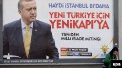 Турецкая женщина стоит у плаката с изображением Реджепа Эрдогана и со слоганом "Давай, Турция, еще один раз". Стамбул, 21 марта 2014 года.