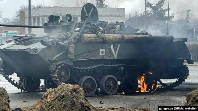 A Russian armored vehicle with dead soldiers stands destroyed in a street during the battles for Hostomel.