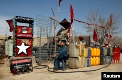 A boy sits next to plastic canisters filled with petrol that he says was brought from Iran, while waiting for customers at a roadside petrol station on the outskirts of Quetta.