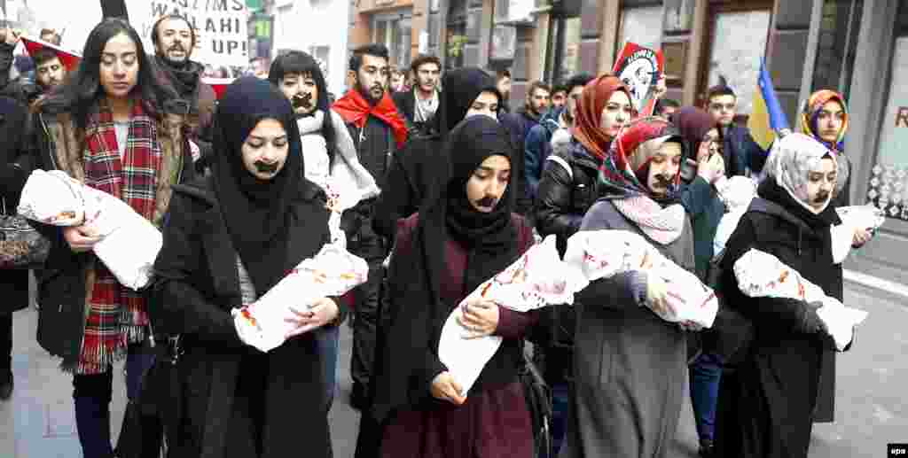 Young Bosnian women hold baby dolls wrapped in white fabric with stains symbolizing blood as several thousand Bosnian protesters gather to raise their voice against the killing in eastern Aleppo, Syria, during a rally in Sarajevo on December 14. (epa/Fehim Demir)