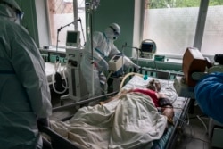 Лікарі, одягнені в спеціальні костюми для захисту від коронавірусу, готують пацієнта з коронавірусом до рентгенографії легень у відділенні інтенсивної терапії в обласній лікарні в Чернівцях, 4 травня 2020 року