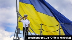 Матрос ВМС на тлі величезного прапора України на фрегаті «Гетьман Сагайдачний» під час навчань «Сі Бриз-2018». Одеса, 16 липня 2018 року