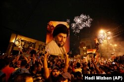 Followers of Shiite cleric Muqtada al-Sadr, seen in the poster, celebrate in Tahrir Square, Baghdad, Iraq, early Monday, May 14, 2018