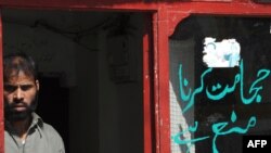 A barber stands by a “do not shave" warning written by the Taliban in the front window of his shop in Buner district, Pakistan.