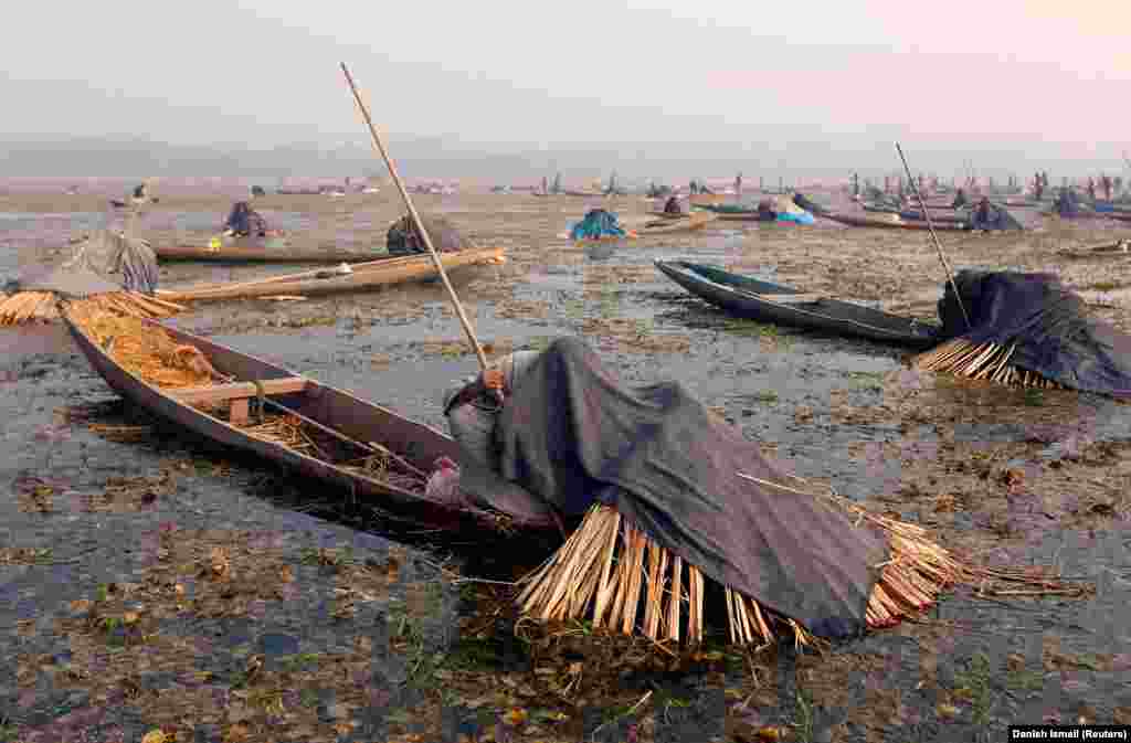 Рыбакі прыкрываюць свае галовы і чаўны коўдрамі і саломай падчас лоўлі рыбы ў водах возера Анчар у халодны зімовы дзень у Срынагары (Reuters)