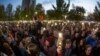 Demonstrators wave their phones as they gather in front of a fence backed by police during a protest against plans to construct a cathedral in a park in Yekaterinburg on May 15.