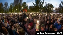 Demonstrators wave their phones as they gather in front of a fence backed by police during a protest against plans to construct a cathedral in a park in Yekaterinburg on May 15.