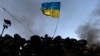 An antigovernment protester waves a Ukrainian flag behind a roadblock in Kyiv on January 27.