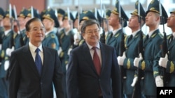 China's Prime Minister Wen Jiabao (left) and his Kyrgyz counterpart review Kyrgyz honor guards at Manas airport in December, 2012.