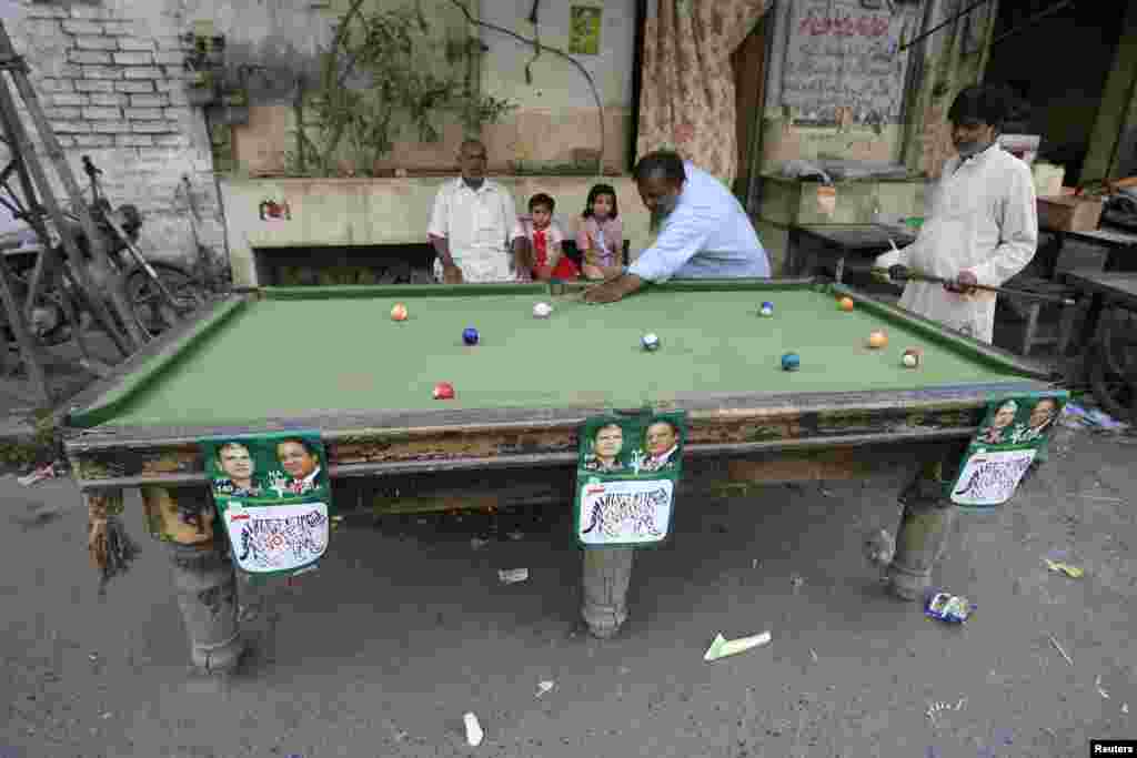 Men play pool in Pakistan on a table decorated with campaign posters. Pakistan&#39;s general elections will be held on May 11. (Reuters/Mani Rana) 