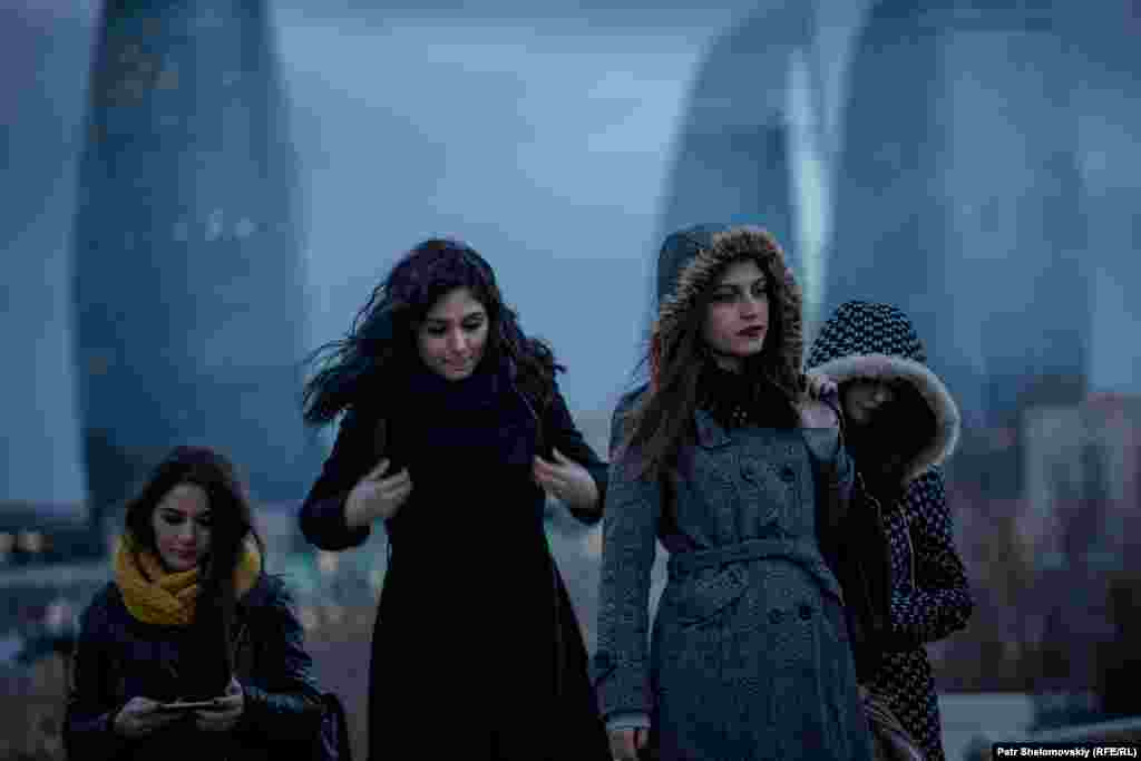 Girls walk on the Caspian Sea embankment in Baku. The distinctive Flame Towers can be seen in the background.