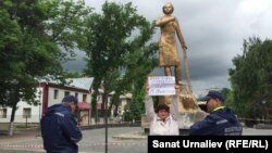 Полицейские наблюдают за активистом Оксаной Терновской, протестующей против сноса памятника герою Второй мировой войны Маншук Маметовой. Уральск, 22 мая 2017 года. 